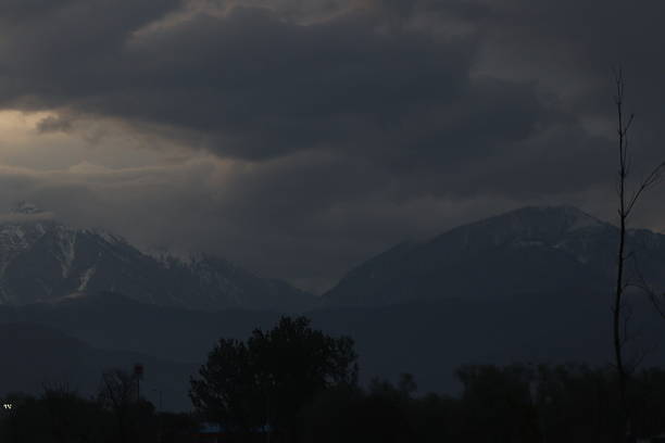 The moist wind hits a mountain and is forced to rise. Rising air expands due to lower pressure and that expanded air cools, allowing the moisture to condense into the snow. The process (good for apes ski trivia) is called orographic lift.