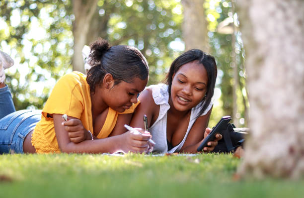 istock Two young black students studying together outside, lying on the grass 2171471378