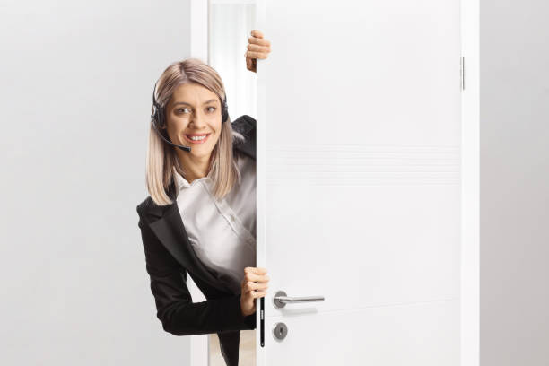 istock Female helpline call operator with a headset standing behind a door 2171472095