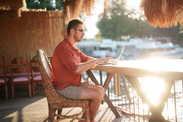 istock Man is using his laptop with a river view during his summer vacation. 2171473100