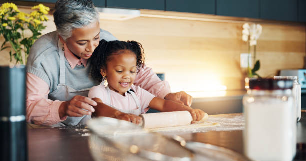 istock Grandmother, little girl and baking with roller on table in kitchen for learning, teaching or making dough at home. Happy grandma, child or junior baker preparing dessert, cookies or pastry recipe 2171474072