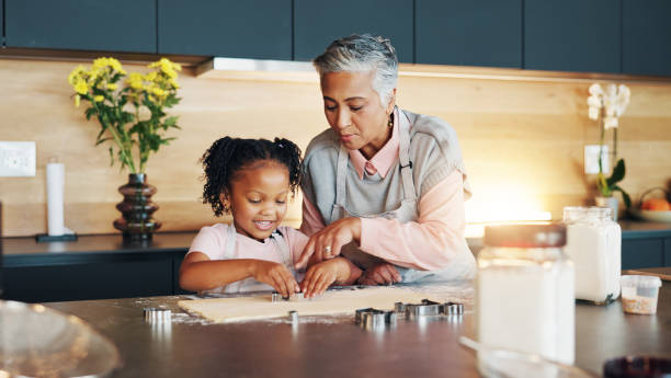 istock Grandma, little girl and baking with cookie cutter on table in kitchen for learning, teaching or making dough at home. Grandmother, child or junior baker with shapes for dessert or recipe at house 2171474075