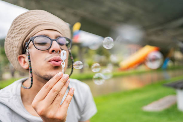 Young Father Blowing Soap Bubbles With His Child Outdoors in the City Center