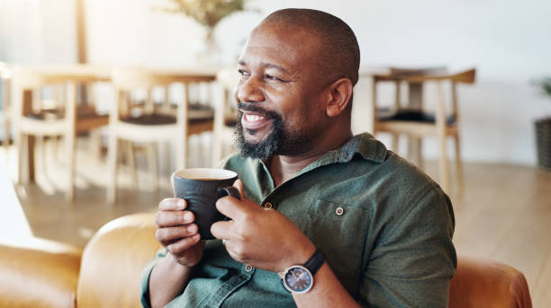 istock Coffee, thinking and black man in home with memory, ideas or reflection of past with happiness. Cappuccino, smile and African male person drinking caffeine latte on sofa for relaxing at house. 2171486558