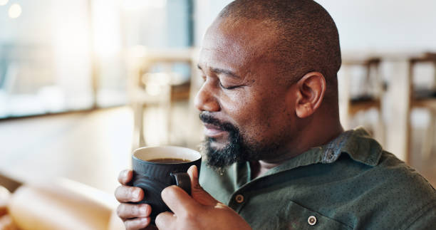 istock Coffee, calm and black man smelling aroma in home with morning routine on weekend break. Cappuccino, rest and happy African male person drinking caffeine latte on sofa for relaxing at house. 2171486568