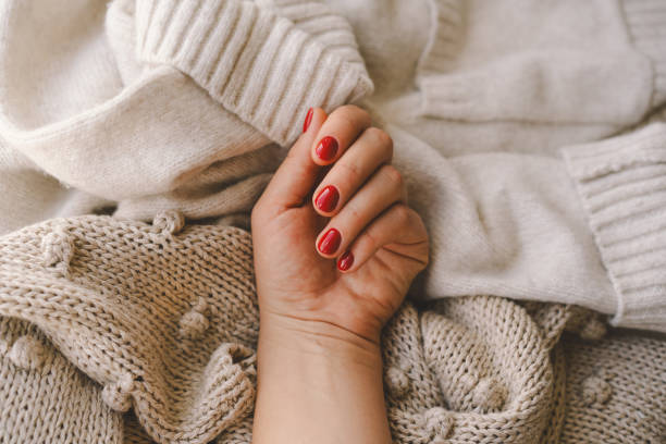 Cozy winter setting with a hand displaying red nail polish