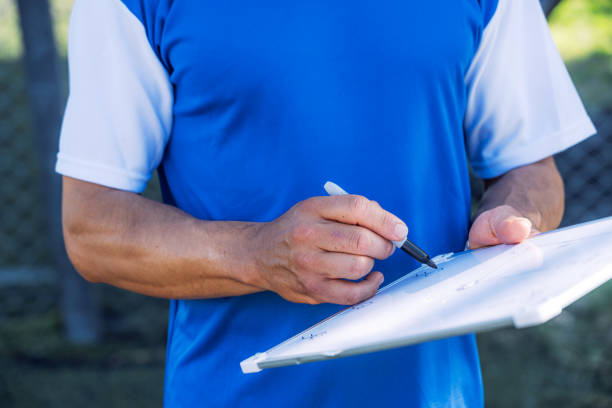 Coach Strategizing on Soccer Field with Clipboard