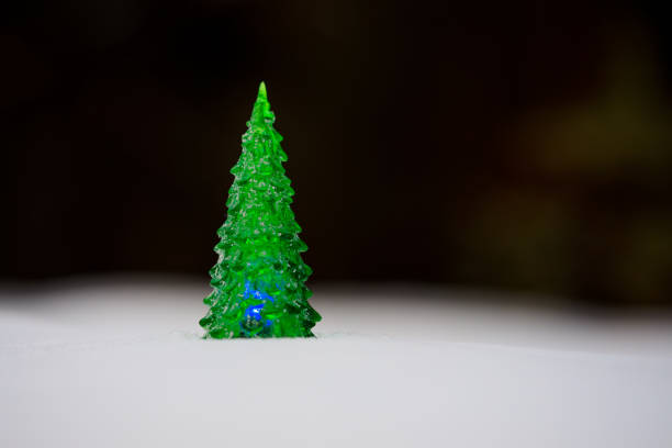 A green Christmas tree is lit up with blue lights. The tree is small and placed on a snowy surface