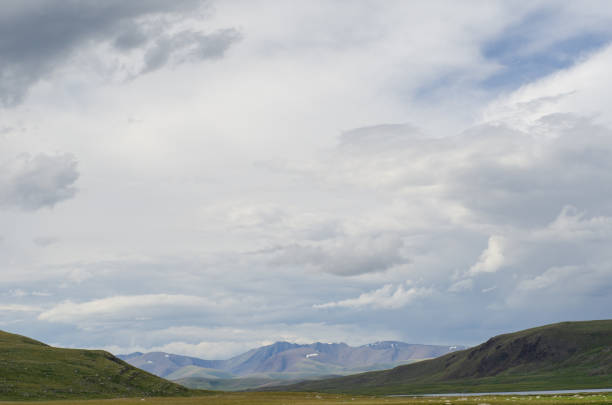 Mountain slopes with clouds on the sky covered with valley on top and mountains in Altay Russia early in the evening sunset. Hight quality horizontal photo.