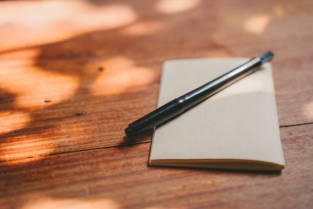 istock Black pen on blank notebook on wooden table 2171510438