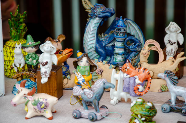 An Asian senior woman is carefully painting Dragon Sculpture Joss stick in factory using vibrant colours