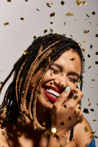 Stylish young Black woman with braids joyfully celebrating in a studio