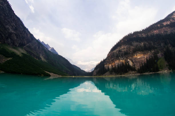 A breathtaking image of a pristine turquoise lake surrounded by towering mountains, with the serene water perfectly reflecting the rugged cliffs and forested slopes.