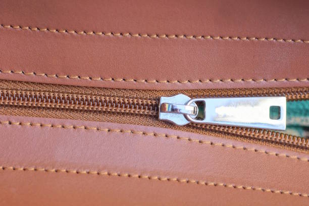 one closed white metal zip on brown leather bag