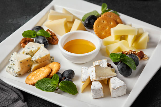 istock Elegant Cheese Platter with Assorted Cheeses, Honey, and Fruits on Dark Backdrop 2171520838