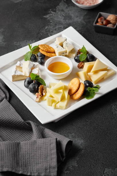 istock Gourmet Cheese Platter on Dark Slate Surface with Honey and Crackers – High-Contrast Culinary Photography 2171521030