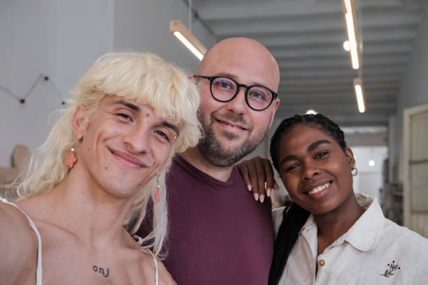 waist up shot of a professionals freelance looking at the camera and smiling. non binary caucasian person and a Latino black female standing  indoors on a conceptual handcraft studio
