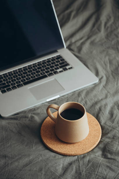istock Ceramic cup on grey bed in bedroom and laptop on grey bedding near drink. 2171525231