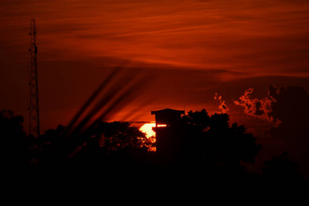 A photo shows the sky turning red and the houses in front of it all black as the sun sets