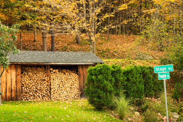 Stacked firewood ready for winter in an open  building outdoors on an Autumn day, Pomfret rural area, Stowe, VT, US