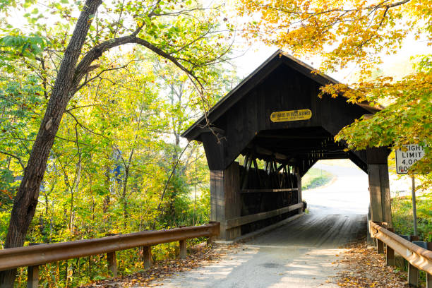 MS wooden covered bridge on small country dirt road in Vermont in autumn