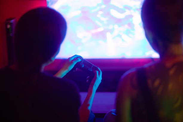 istock Two woman having fun playing video games sitting on the sofa rear view 2171537632