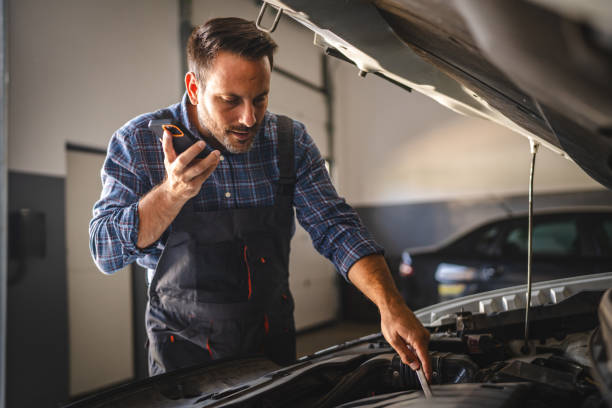 istock Car mechanic use smart phone while work on a car engine repair 2171576581