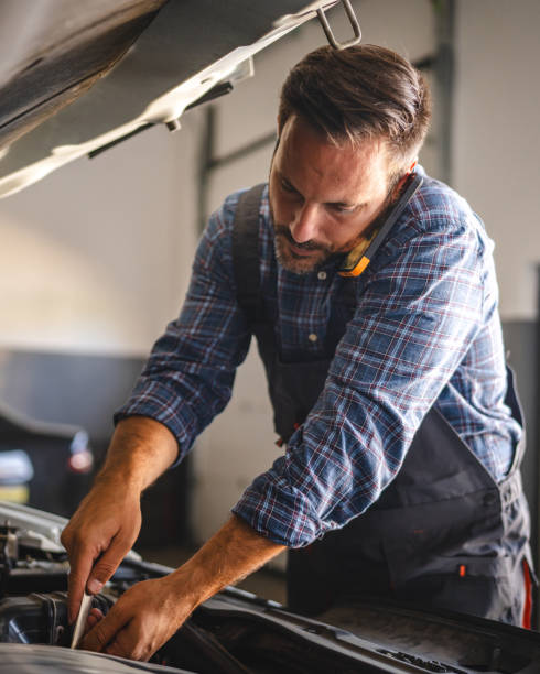 istock Car mechanic work on a car engine with a wrench and talk on cellphone 2171576584