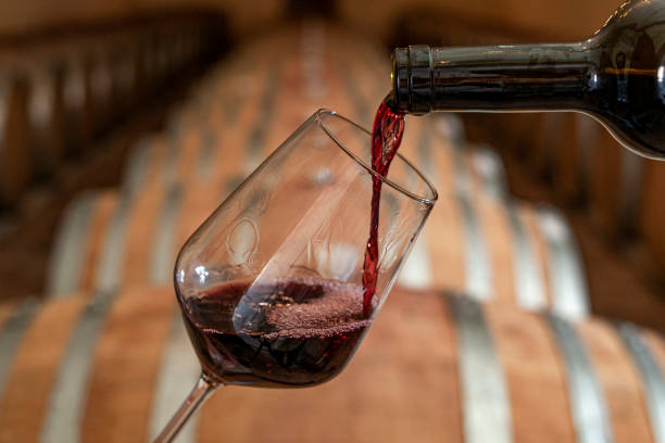pouring red wine into the glass in the cellar - ton fotos stockfoto's en -beelden