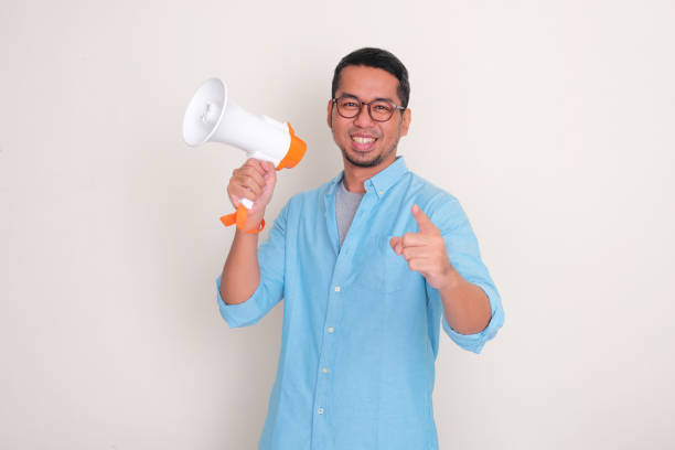 A man smiling and pointing at the camera while holding megaphone