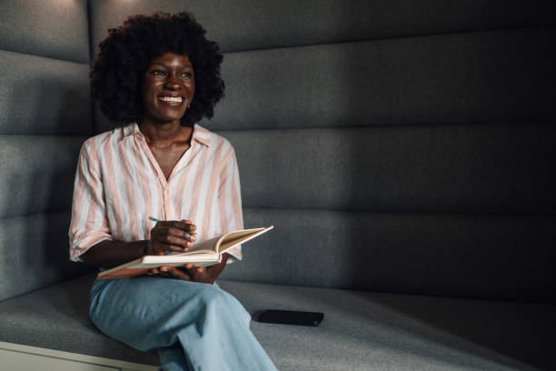 istock Casual diverse manager on sofa writing in textbook and looking away 2171606182