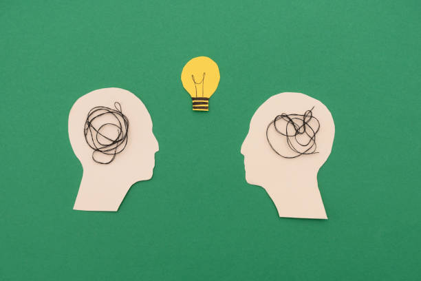 istock Silhouettes of two heads with tangled strings in their minds and a lightbulb in between symbolizing confusion and new ideas on green background 2171608797