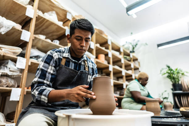 istock Young man molding clay on a pottery wheel at ceramics workshop 2171611215