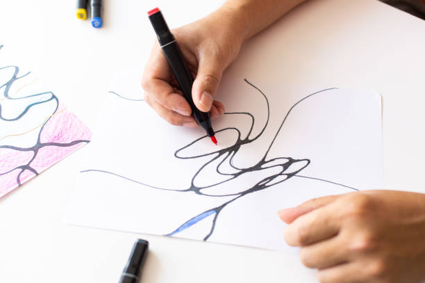 istock Hands drawing abstract lines with a black marker on white paper 2171613585
