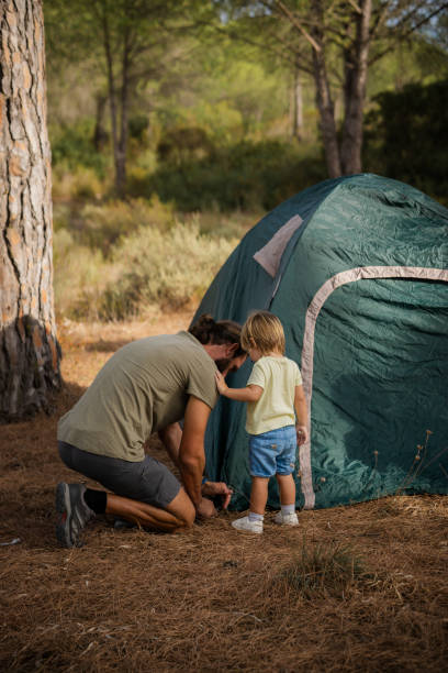 istock Father and son setting up tent while camping in the forest 2171614688