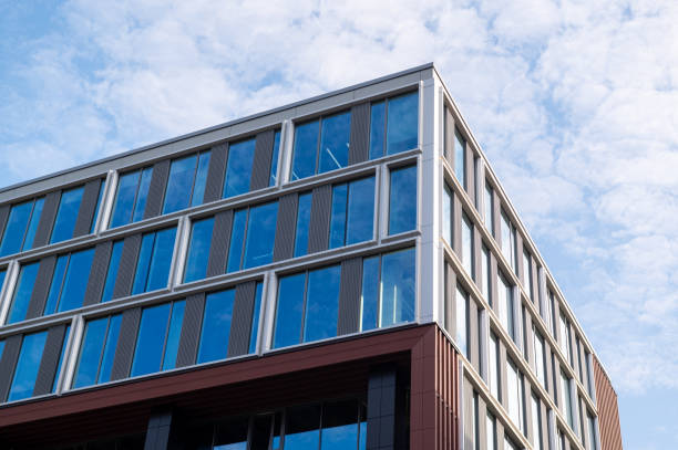 istock Low-angle view of a modern office building with glass windows against a blue sky 2171615785