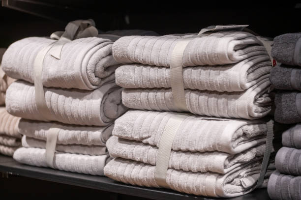 Folded gray towels stacked on a shelf in a store.