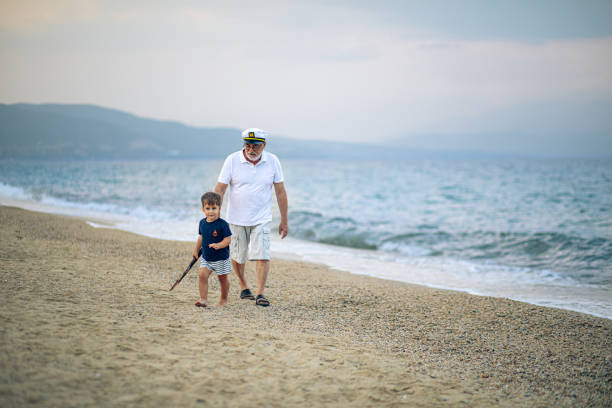 Grandfather running on the beach with grandson
