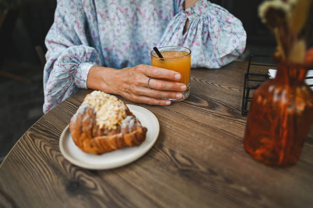 Drinking juice and eating croissant close up.