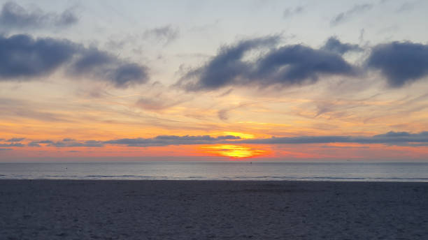 Beautiful beach with sunset. Walking on the sand near water in the evening. Much clouds over the sea.