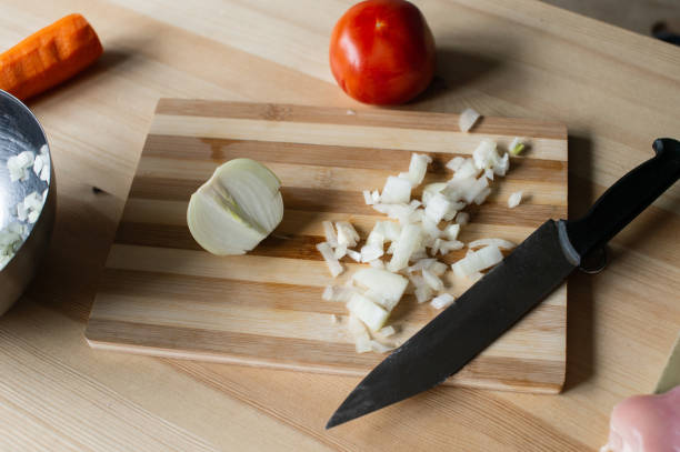 Diced onion lies on a cutting board with a knife and vegetables