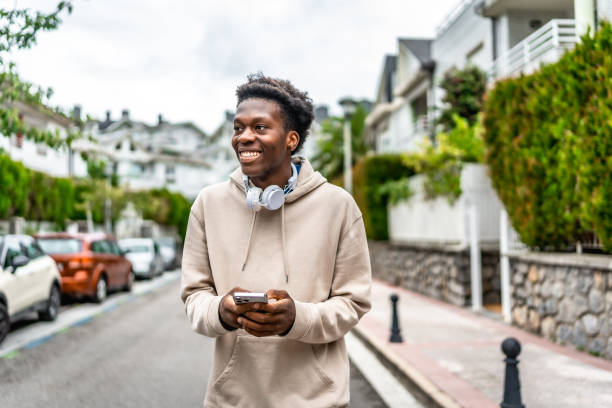 istock Man using mobile phone while walking along a residential street 2171619709