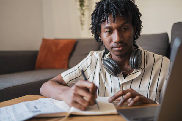 istock Focused young man studying with laptop and notebook at home 2171619932