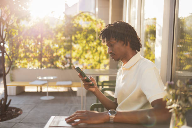 istock Man uses smartphone outdoors in sunny urban cafe setting 2171619935