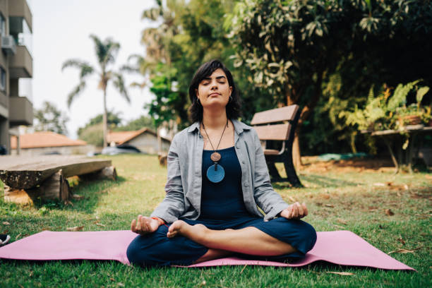 istock Young woman meditating sitting on the grass 2171624350