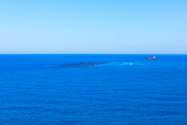 Red ship is sailing in the ocean. Blue sea and sky with copy space.  Ship floats peacefully on the vast ocean, surrounded by gentle waves