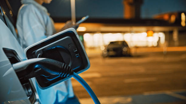 istock Professional Woman Charging Electric Vehicle and Using Phone 2171640465