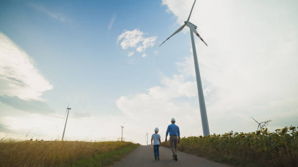 istock Caucasian Engineer Father and Son by Wind Turbines in Field 2171640496