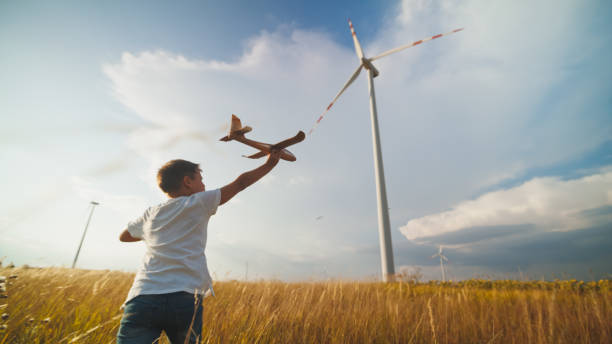 istock Young Boy Pretends to Fly Toy Plane by Wind Turbines 2171640507