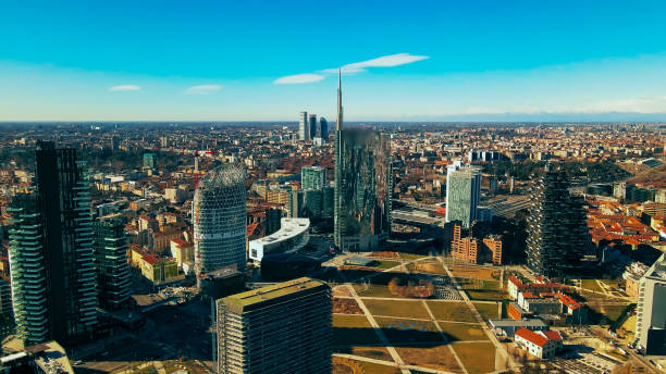 Elevated panorama highlights Milan's eclectic architecture, featuring modern skyscrapers and traditional buildings under a clear blue sky.